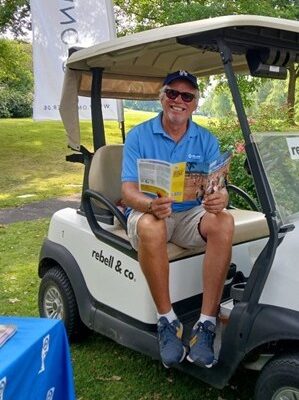 1. CUPEVA Golfturnier in Essen. Udo Stauber mit Flyer auf Golf-Kart