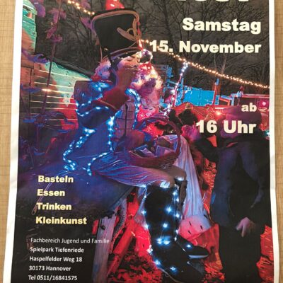 Ein farbenfrohes Plakat wirbt für das Lichterfest mit einem Darsteller in einem großen Hut, der von bunten Lichtern angestrahlt wird. Die Veranstaltung findet am Samstag, den 15. November, ab 16:00 Uhr mit Kunsthandwerk, Essen, Trinken und Kunst im Spielpark Tiefenriede in Hannover statt. Kontaktinformationen sind unten aufgeführt.