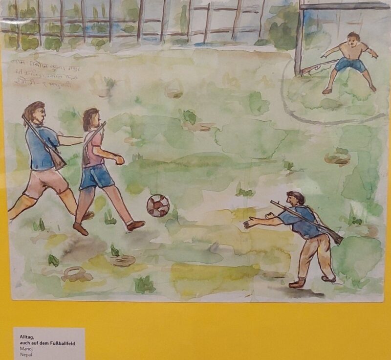 Ein Aquarell zeigt vier Kinder beim Fußballspielen im Freien. Drei Kinder jagen einen Ball auf grünem Gras, während ein viertes mit ausgestreckten Armen in einem Tor steht. Im Hintergrund sind ein Zaun, Bäume und schwache Berge unter einem blassblauen Himmel zu sehen.