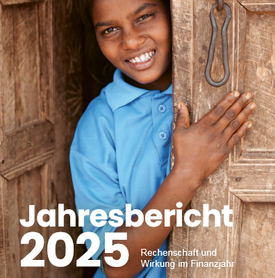 Ein lächelndes Mädchen in einem blauen Hemd steht in einer Tür und stützt sich mit einer Hand auf die Holztür und mit der anderen auf den Türrahmen. Der weiße deutsche Text lautet "Jahresbericht 2025. Rechenschaft und Wirkung im Finanzjahr". Darüber erscheint das Logo von Plan International.