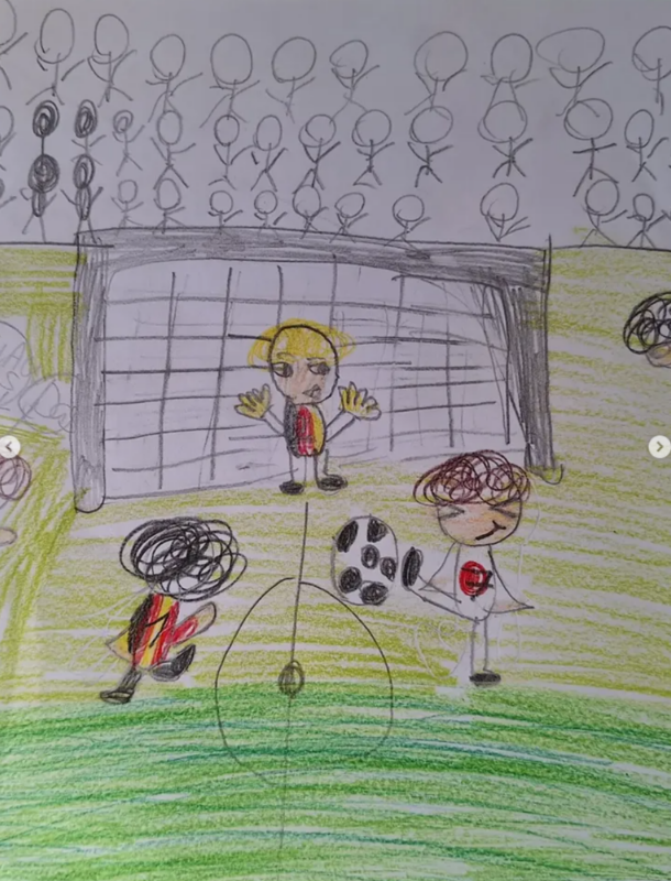 Eine Kinderzeichnung eines Fußballspiels: Ein Torwart in Gelb und Rot steht mit erhobenen Armen vor einem Tor. Zwei Spieler, einer in Schwarz und Rot, einer in Weiß mit einem roten Herz, jagen einem schwarz-weißen Ball hinterher. Die Tribüne hinter dem Tor ist mit Strichmännchen gefüllt.