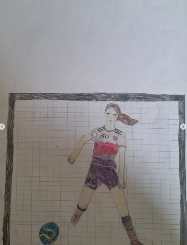 Eine Buntstiftzeichnung einer Fußballspielerin mit braunem Haar, die ein rot-weiß-schwarzes Trikot mit der Nummer 10 trägt. Sie steht vor einem Tornetz und ist dabei, einen blau-gelben Fußball zu schießen. Der Hintergrund ist einfarbig weiß.